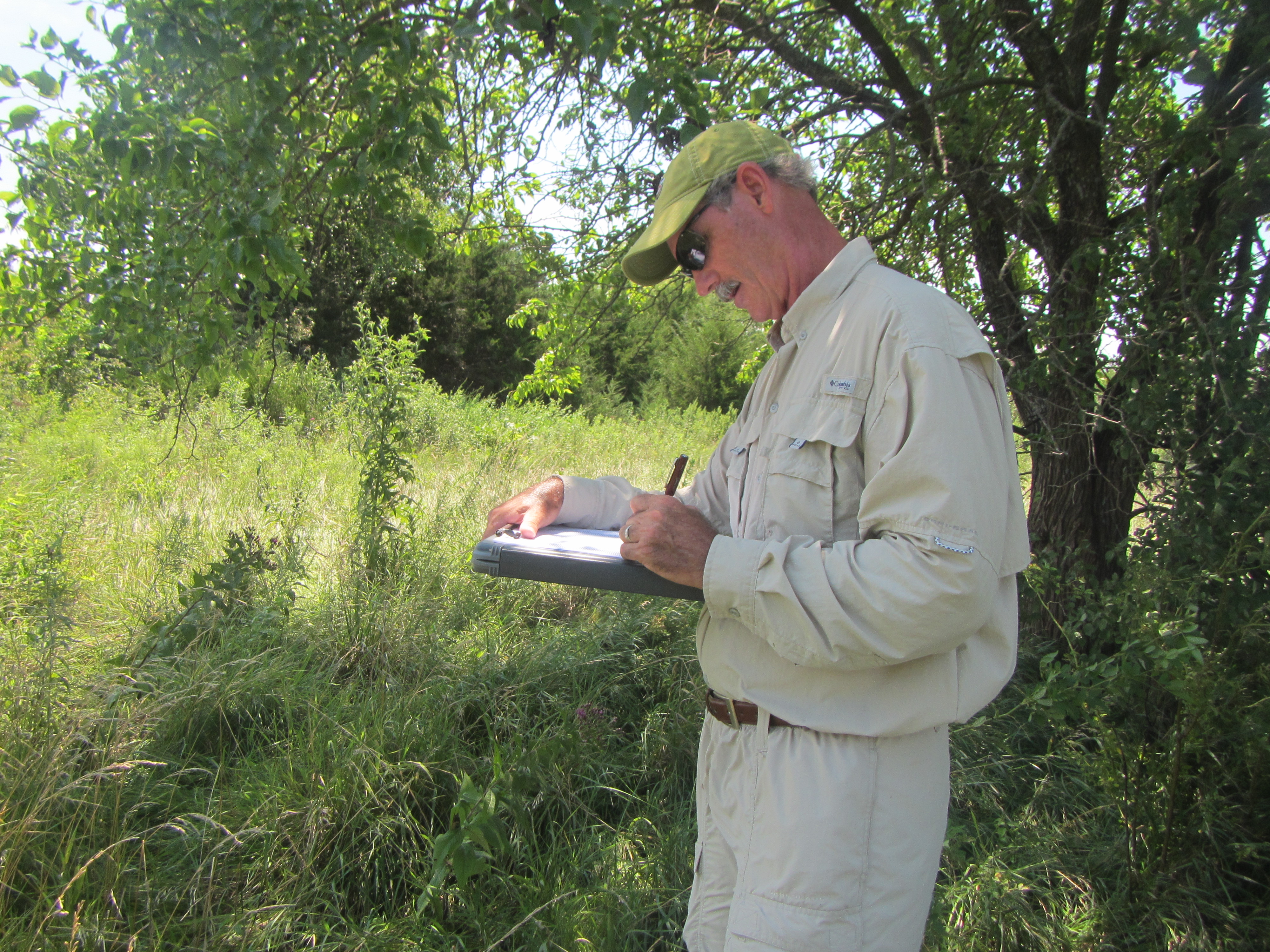 Dr. Craig Freeman records vegetation found around a farm pond in the Delaware River Watershed in Kansas.