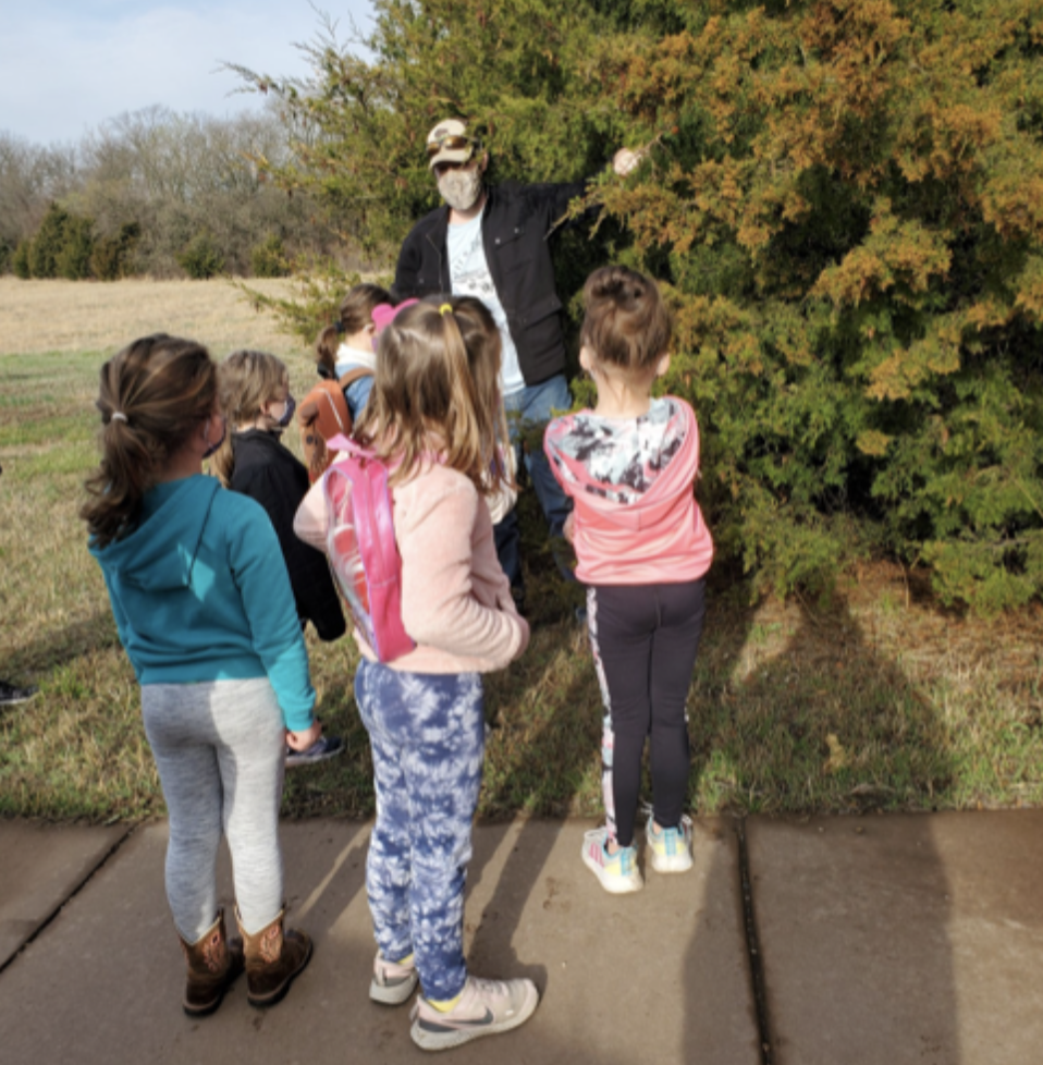 "Nathaniel Weickert talking with a small group of young children on a paved path at the KU Field Station"